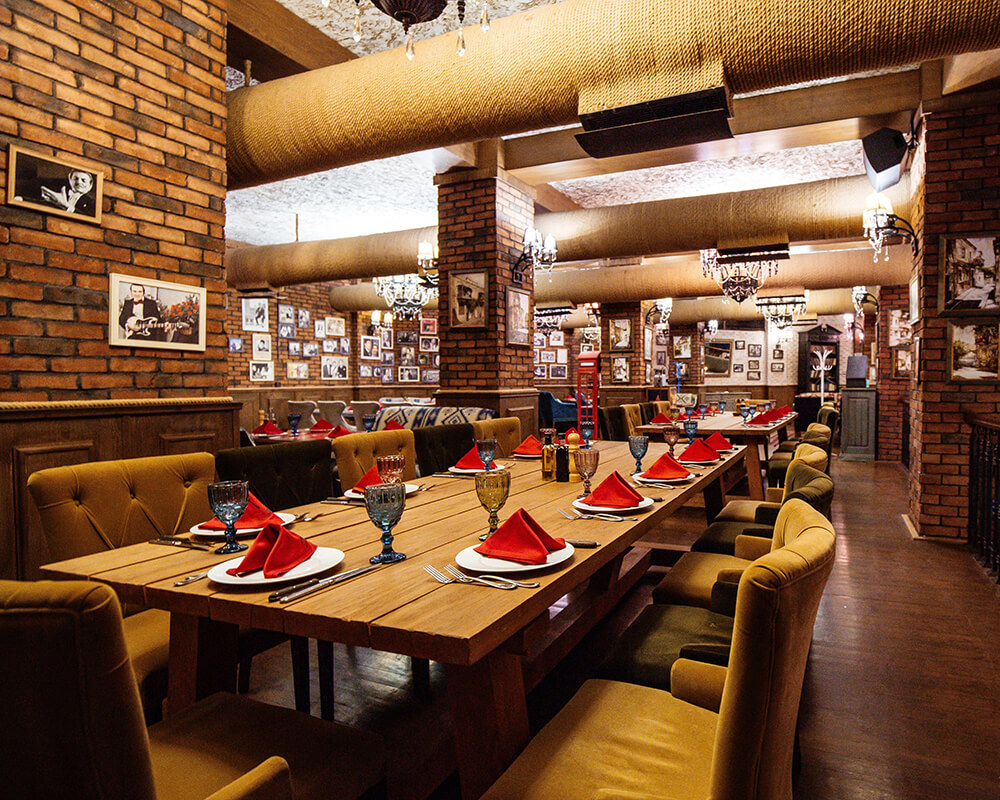 https://capilha.com.br/wp-content/uploads/2024/04/restaurant-hall-with-red-brick-walls-wooden-tables-pipes-ceiling-1.jpg